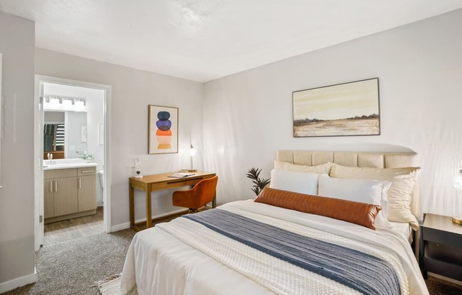 The Grove Apartments bedroom with large bed and two nightstands and desk with bathroom