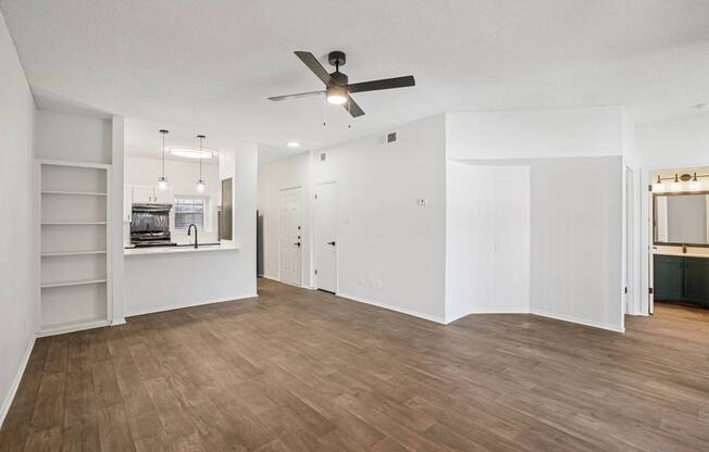 A room with a ceiling fan and wooden flooring.