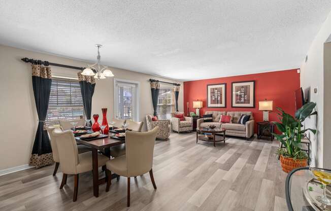 a living room and dining room with red walls and wooden floors