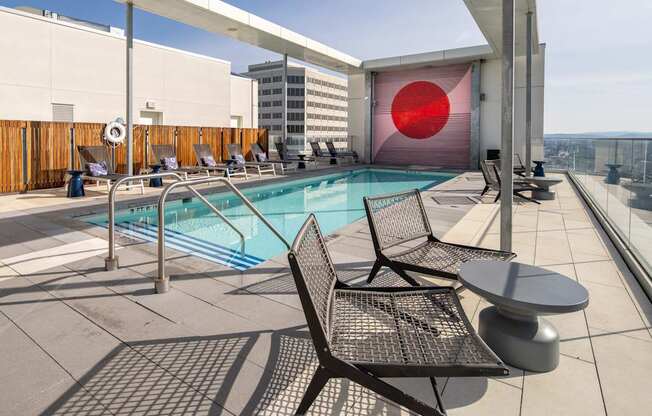 A pool with chairs and a table on a patio.