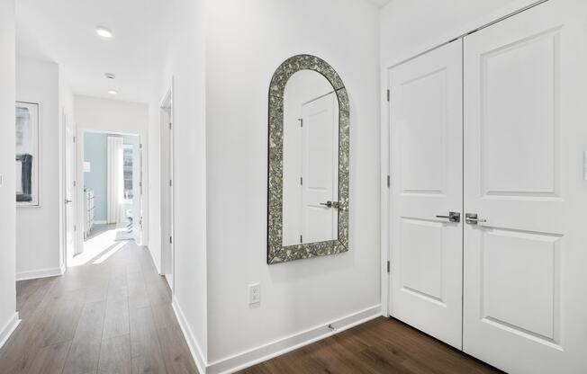 a hallway with white doors and a mirror on the wall