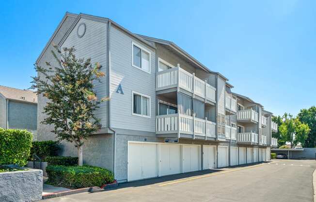 the view of an apartment building with garages and a tree