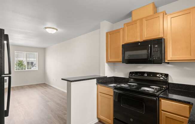 an empty kitchen with black appliances and wooden cabinets