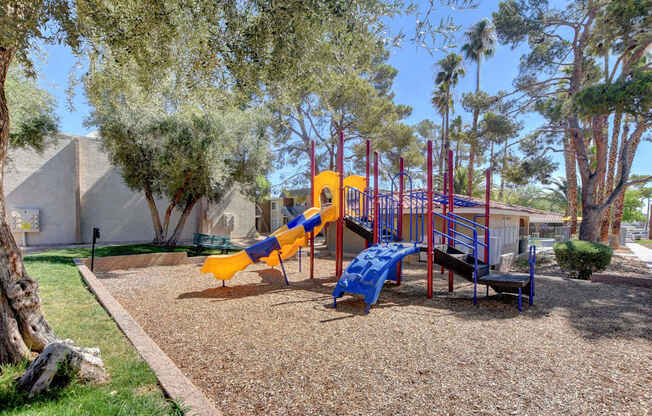 A playground with a yellow slide and a blue bench.