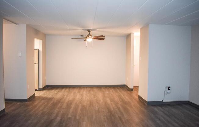 A room with a ceiling fan and wooden flooring.