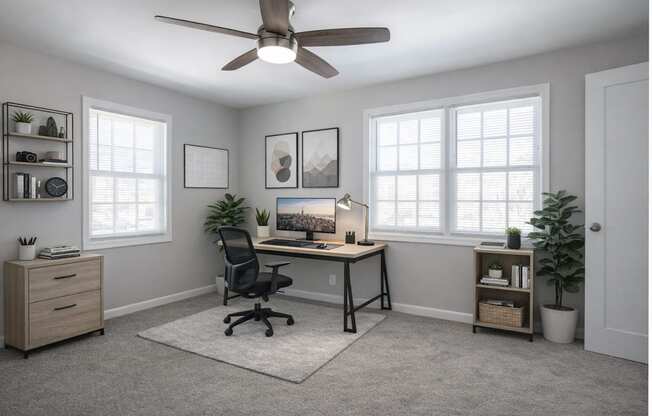A room with a desk, chair, and a ceiling fan.