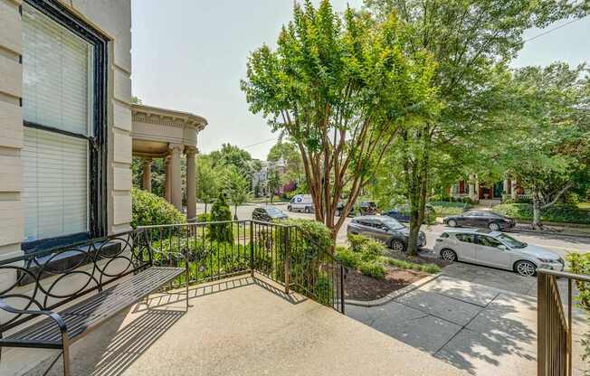 A view of a balcony with a bench and a tree in the foreground.