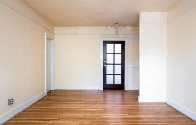 an empty living room with white walls and wood floors