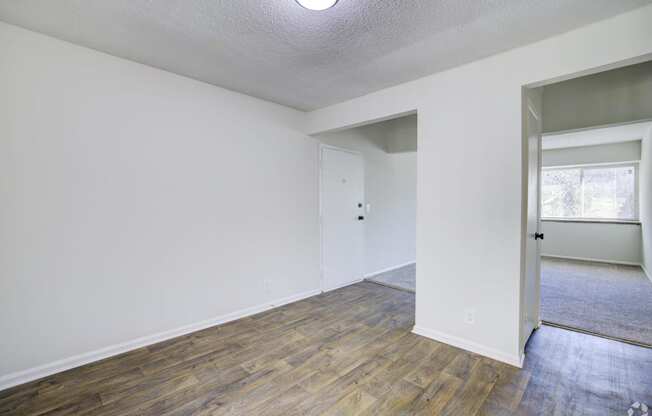 an empty living room with white walls and wood flooring