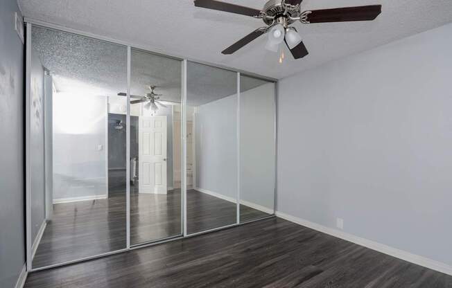 A room with a ceiling fan and sliding glass doors.