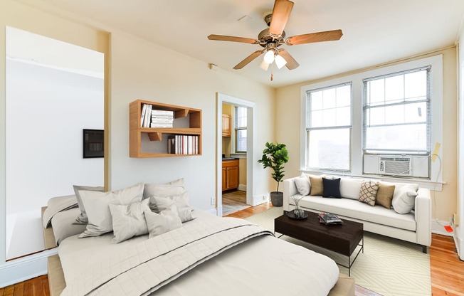 studio apartment showing sofa, bed, ceiling fan, large windows and view of kitchen at the foreland apartments in washinton dc
