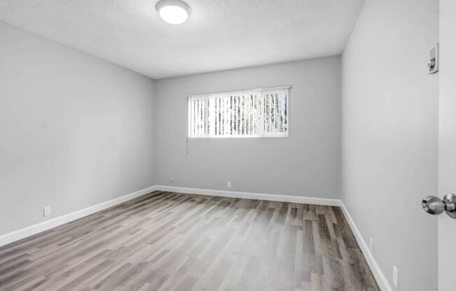 the living room of an empty house with wood flooring and a window