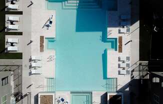 A swimming pool surrounded by lounge chairs and buildings.