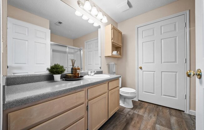 A bathroom with a white toilet, wooden cabinets, and a white door.