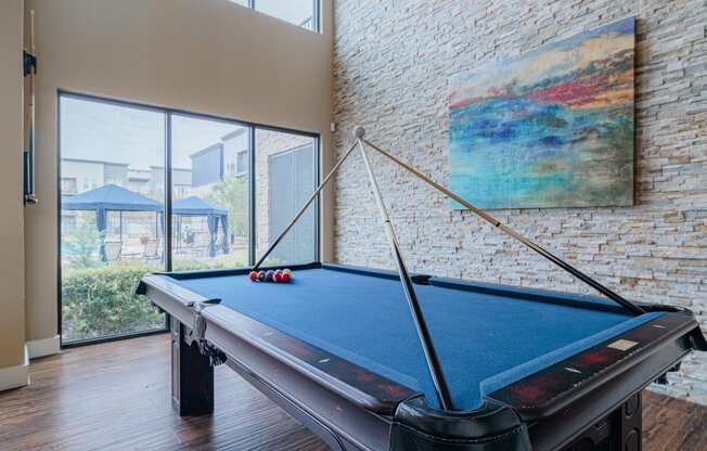 a pool table in a living room with a large window