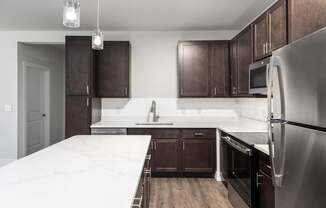 A kitchen with dark brown cabinets and a stainless steel refrigerator.