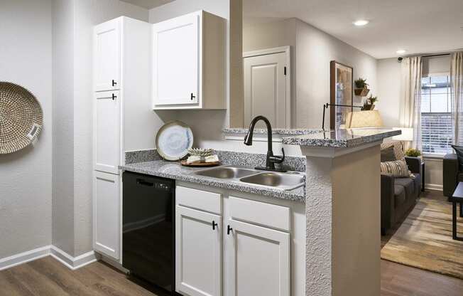 an open kitchen and living room with white cabinets and a counter top