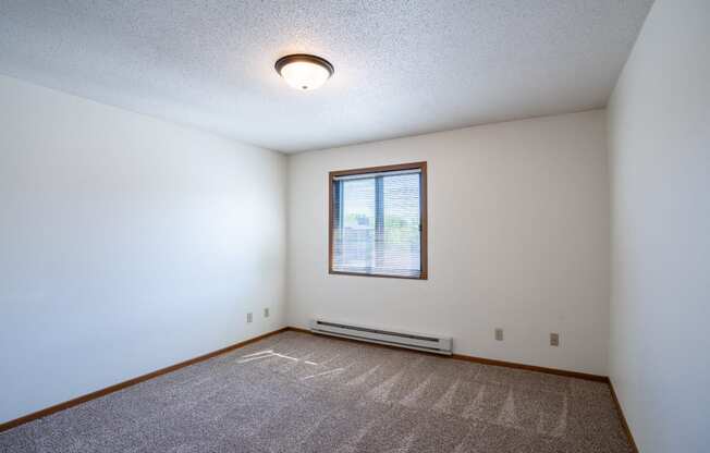 a bedroom with carpet and a window. Fargo, ND Southview Village Apartments