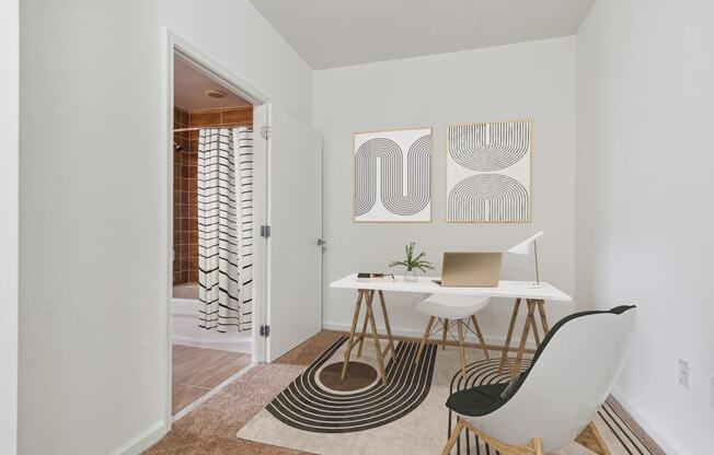 a home office with a desk and chair and a door to a bathroom