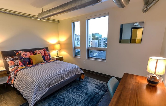 a bedroom with a bed and a desk with two lamps