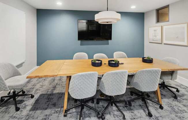 A conference room with a long table and chairs at The Kitt at Warner Center Apartments, Woodland Hills, CA, 91303