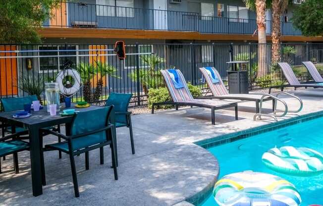 Community pool at fifteen 50 apartments in Las Vegas, NV with lounge chairs and patio umbrellas