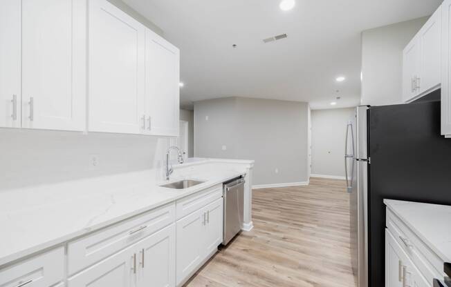 a white kitchen with white cabinets and a black refrigerator