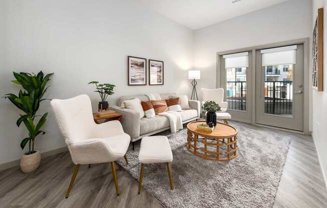 A living room with a grey rug, a white sofa, a white chair and a wooden coffee table.