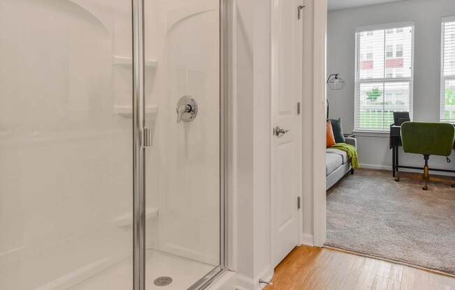 A white bathroom with a glass shower door and a white door.