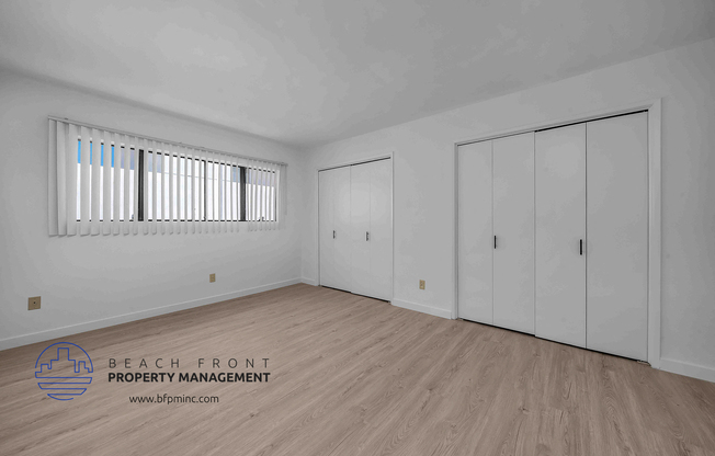 a bedroom with two closets and hardwood floors