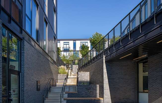a set of stairs between two brick buildings with a blue sky in the background