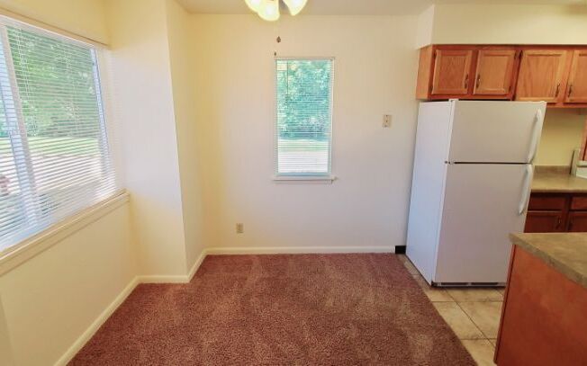 A kitchen with a white refrigerator and brown cabinets.