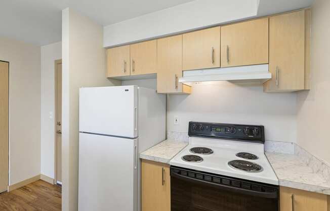 a kitchen with white appliances and wooden cabinets at Guinevere Apartment Homes, Seattle