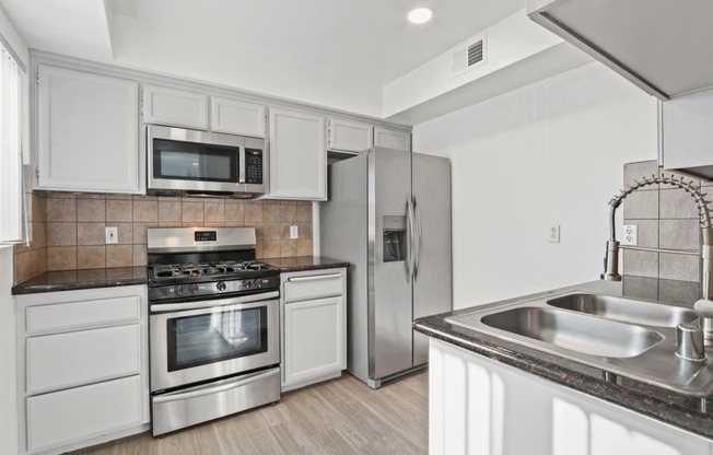 a kitchen with white cabinets and stainless steel appliances