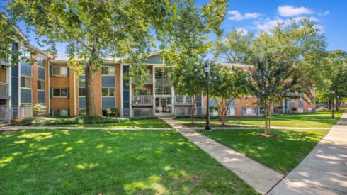 an apartment building with green grass and trees
