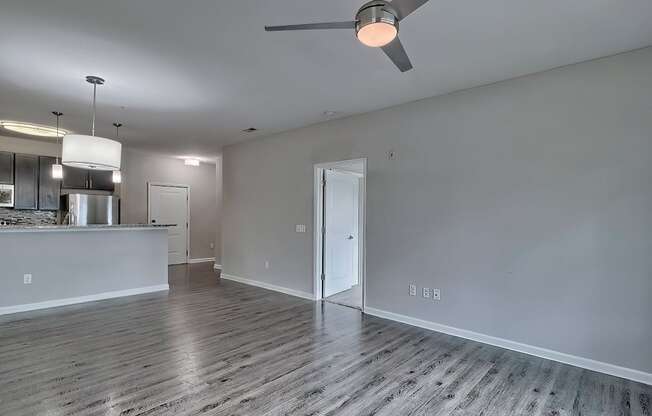 an empty living room with a ceiling fan and a kitchen at Nexus at Sandhill, Columbia, SC 29229