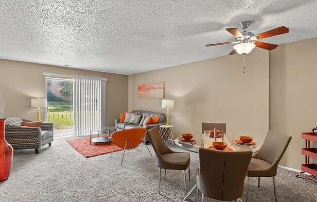 a living room with a table and chairs and a ceiling fan