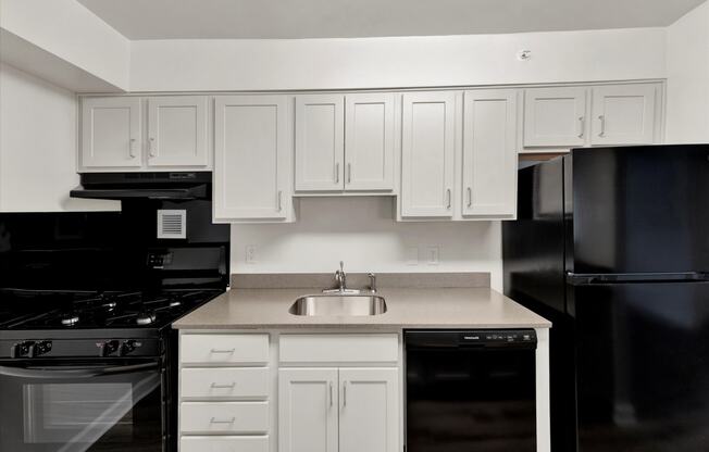 a kitchen with white cabinets and black appliances