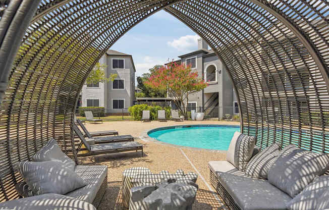A large outdoor seating area with a pool and a building in the background.