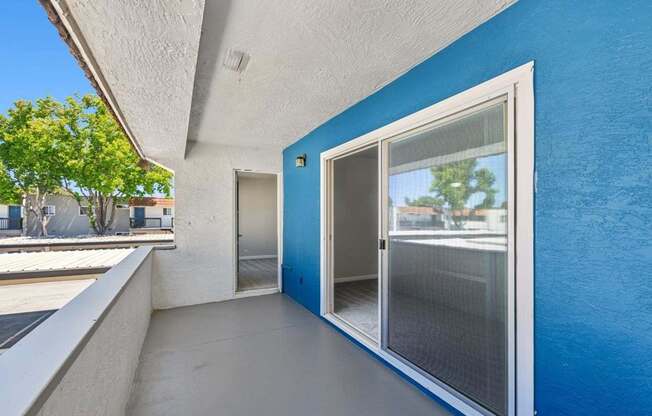 A balcony with a blue wall and a glass door.
