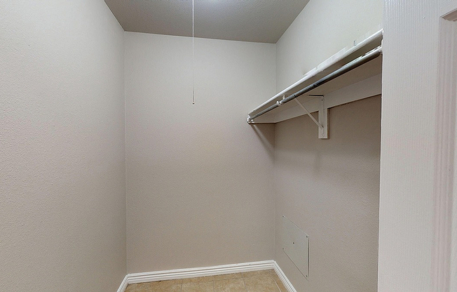 Spacious walk-in closet with neutral tones and ample hanging space, perfect for organizing wardrobe essentials.