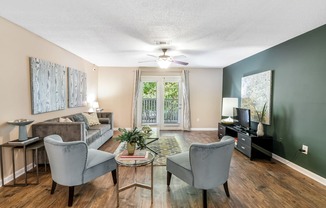 a living room with a couch and chairs and a ceiling fan at Avalon Apartment Homes in Starkville, 39759