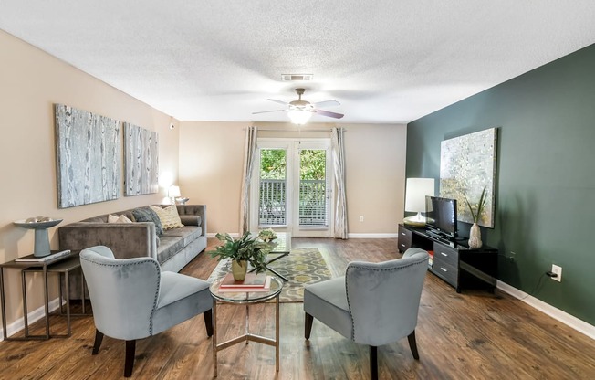 a living room with a couch and chairs and a ceiling fan at Avalon Apartment Homes in Starkville, 39759