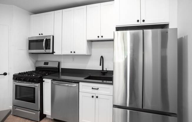 a kitchen with white cabinets and stainless steel appliances