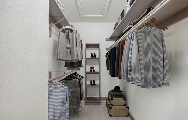 A white closet with clothes hanging and shoes on the floor.