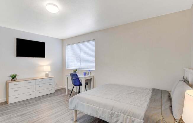 A bedroom with a bed, desk, and chair.