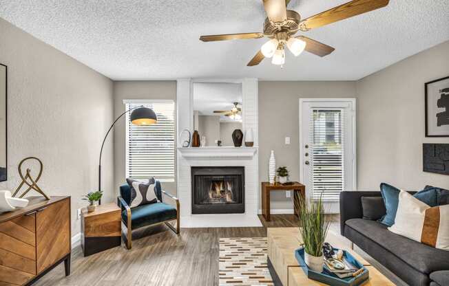 an open living room with a fireplace and a ceiling fan