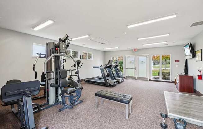 A gym with a variety of equipment including a treadmill, weights, and a bench.