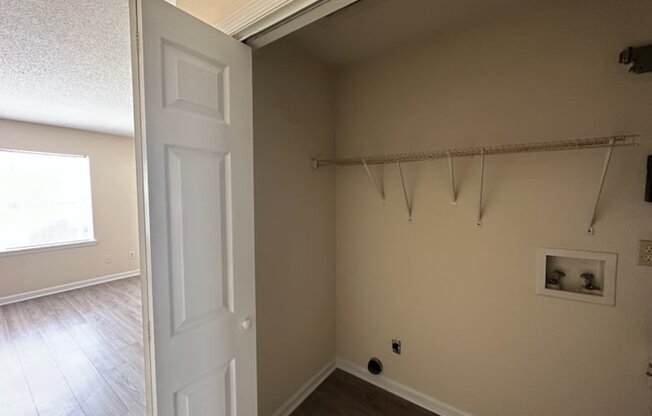 an empty room with a white door and a hallway with wood floors
