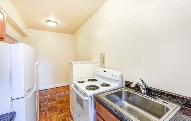 kitchen with wood cabinetry, electric range and refrigerator at eddystone apartments in washington dc